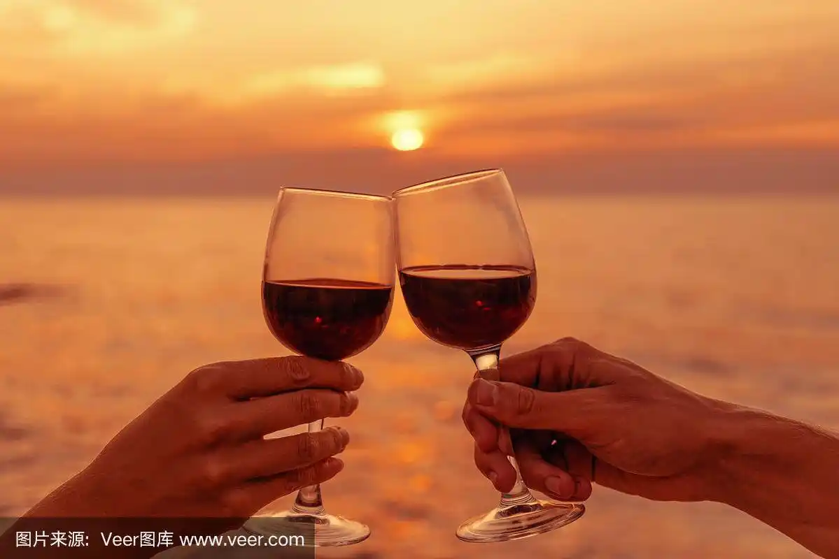 一对情侣在海上夕阳下碰杯.